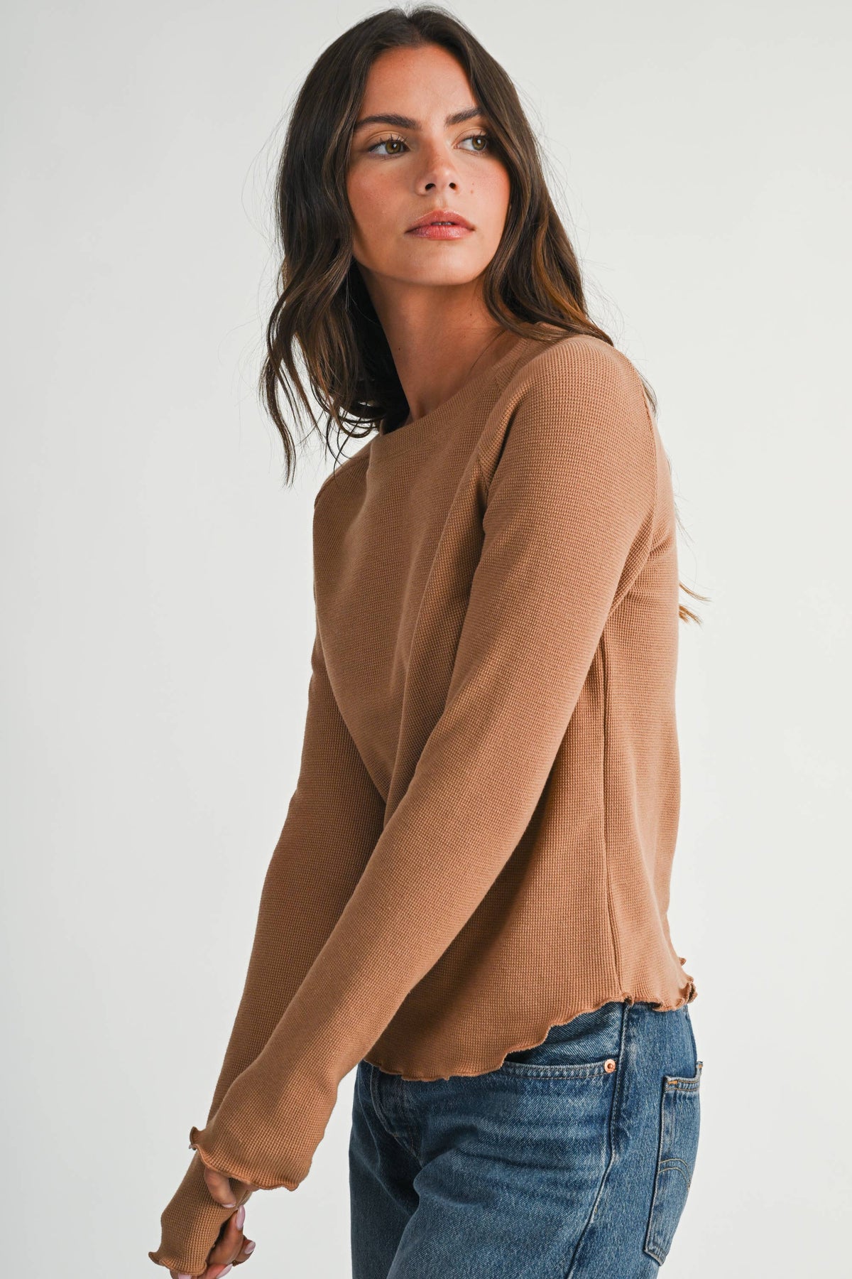 A soft, stylish top featuring a ribbed neckline and lettuce edge detailing.