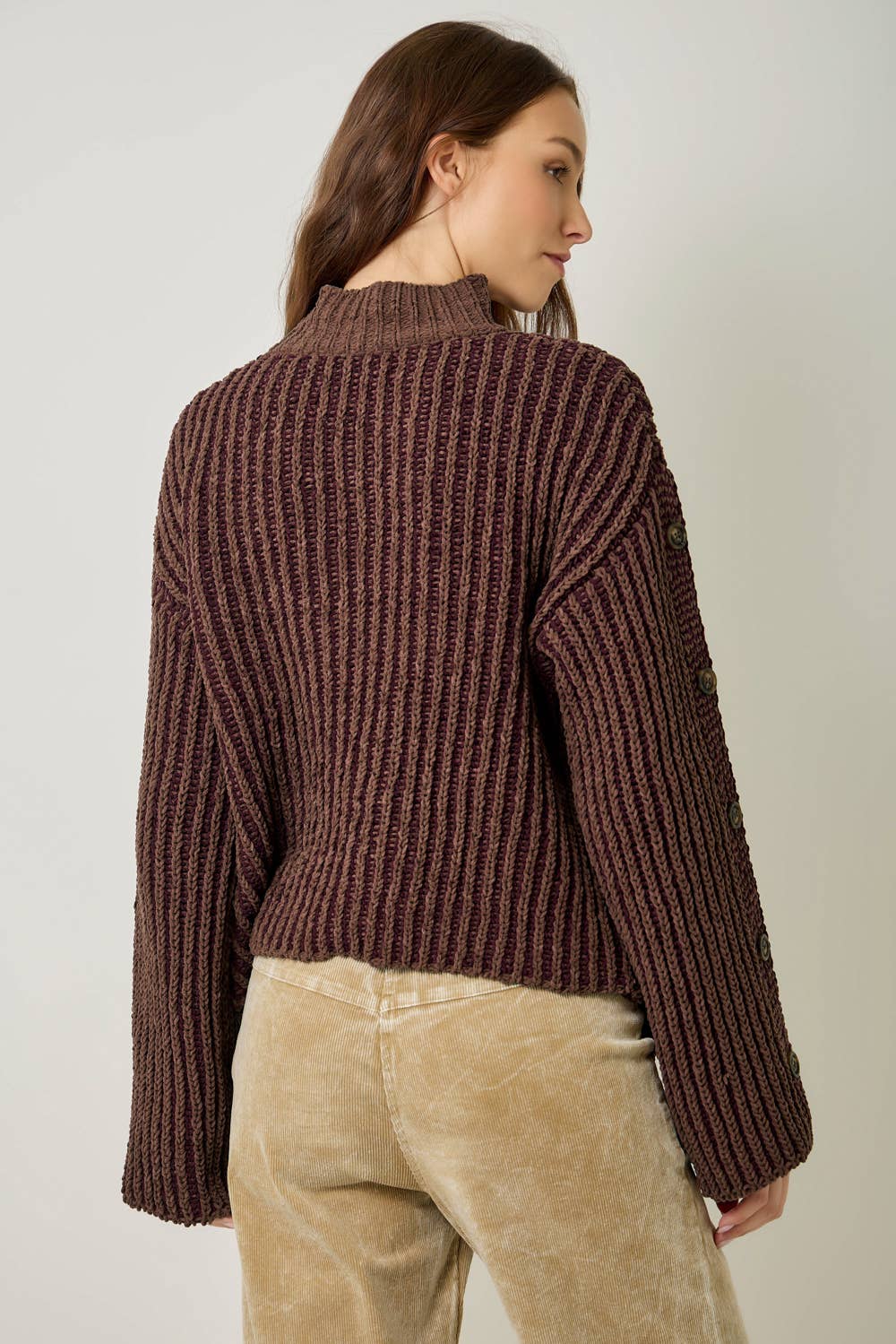 A stylish velvet sweater with color-blocking and decorative buttons.