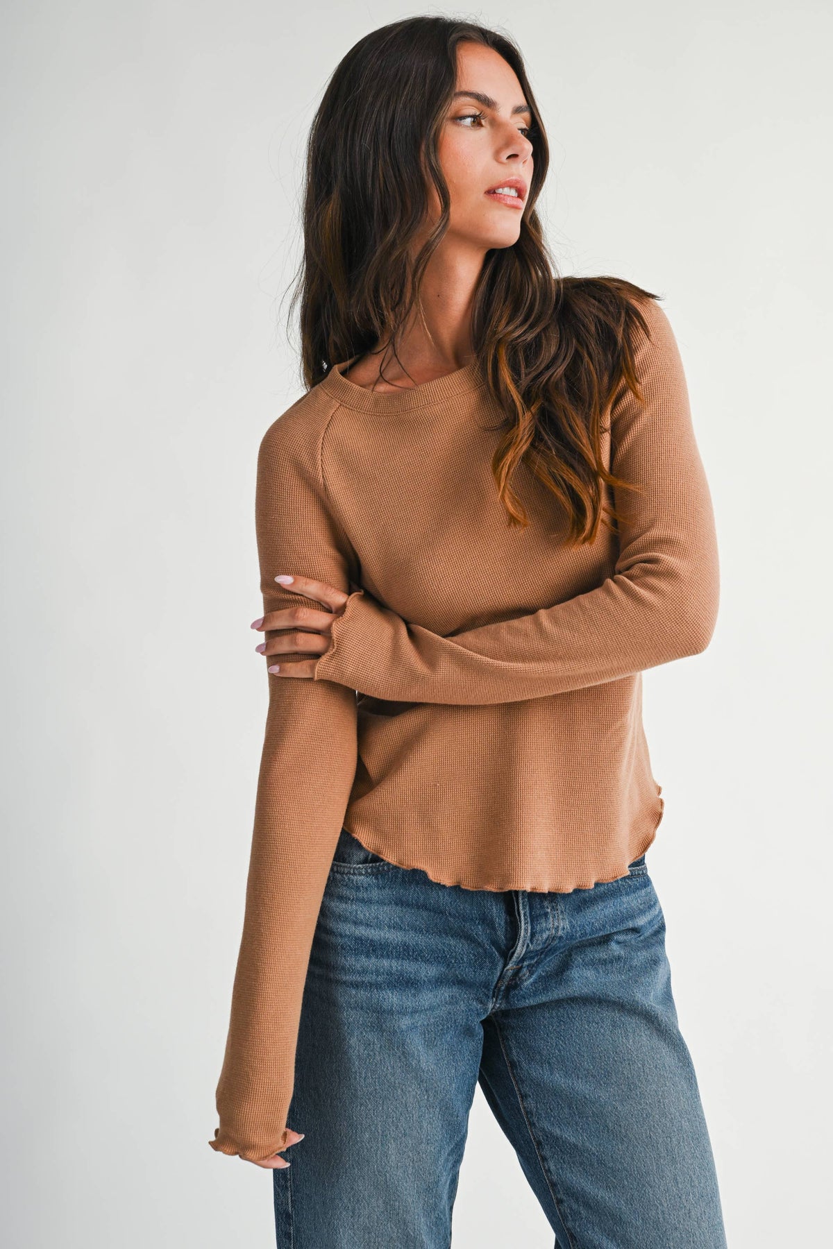 A soft, stylish top featuring a ribbed neckline and lettuce edge detailing.