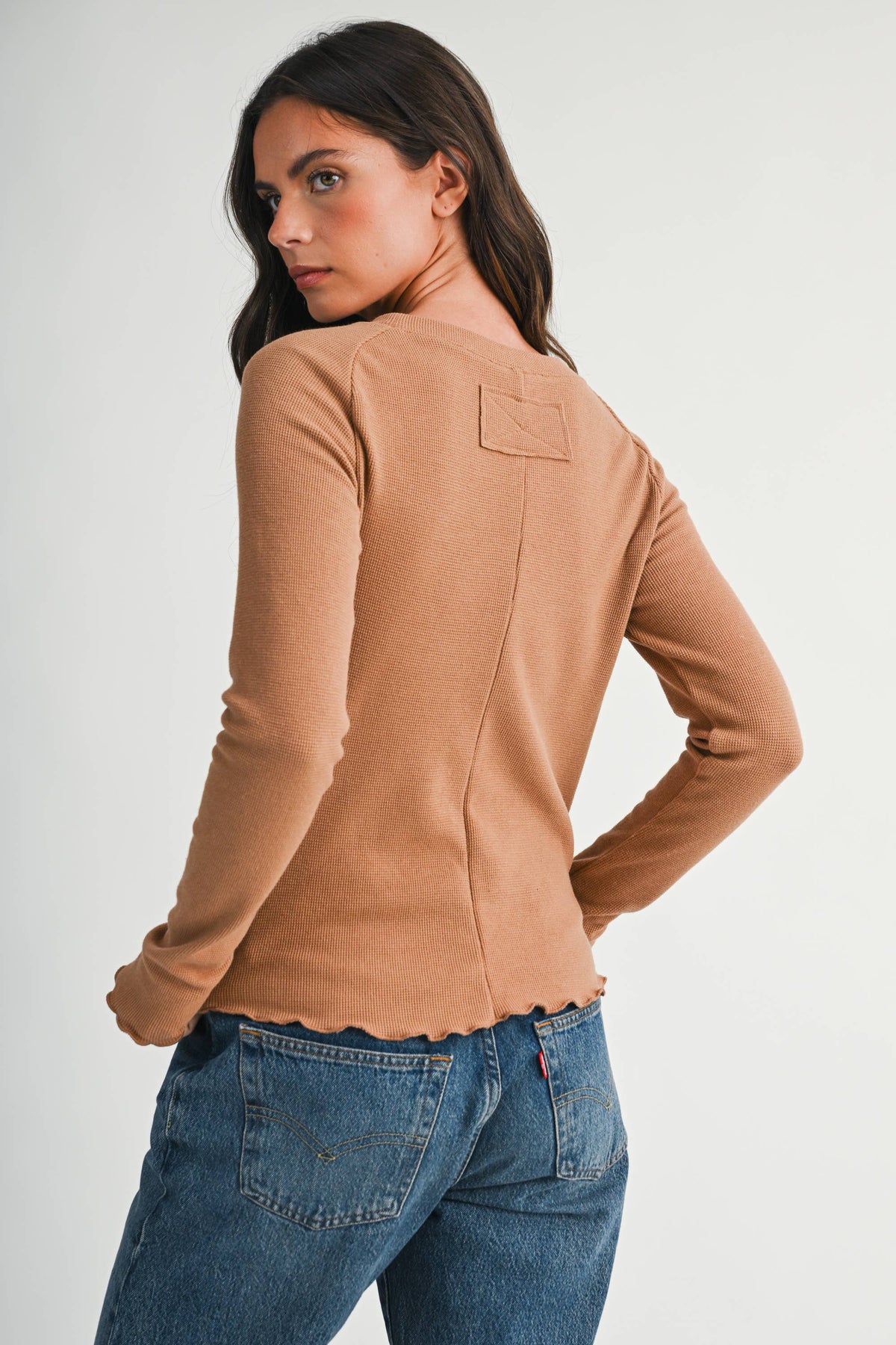 A soft, stylish top featuring a ribbed neckline and lettuce edge detailing.